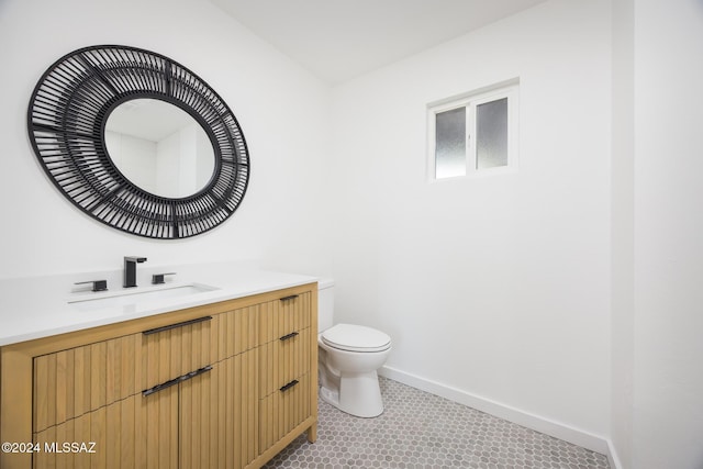 bathroom featuring baseboards, vanity, and toilet
