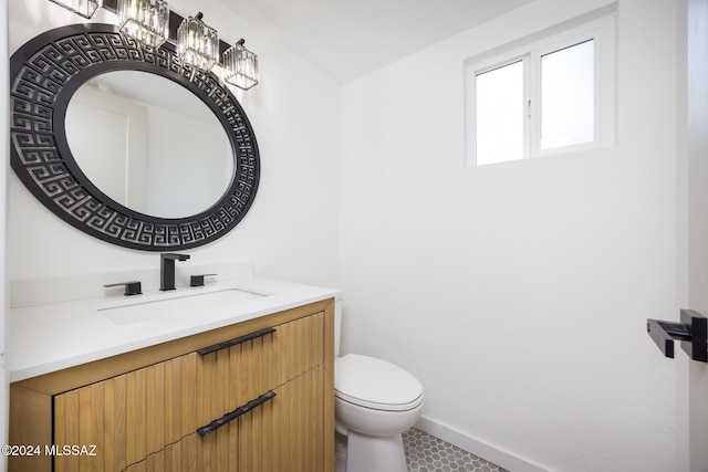 half bath with vanity, baseboards, and toilet