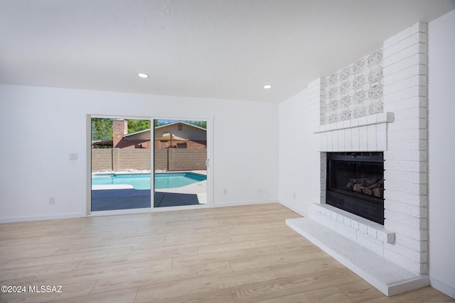 unfurnished living room featuring recessed lighting, baseboards, wood finished floors, and a fireplace
