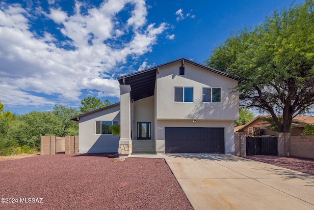 view of front facade with a garage, fence, driveway, and stucco siding