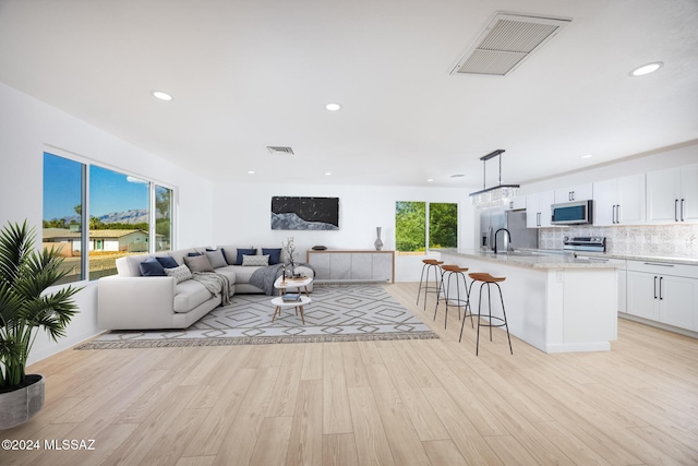 living room featuring recessed lighting, light wood finished floors, and visible vents
