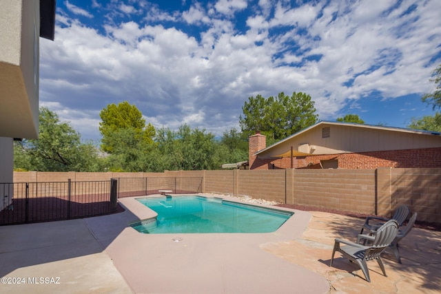 view of pool featuring a patio, a fenced backyard, a diving board, and a fenced in pool