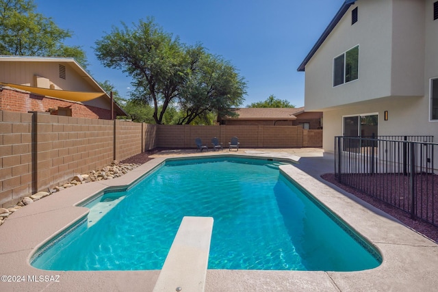 view of pool featuring a fenced backyard, a fenced in pool, a diving board, and a patio area