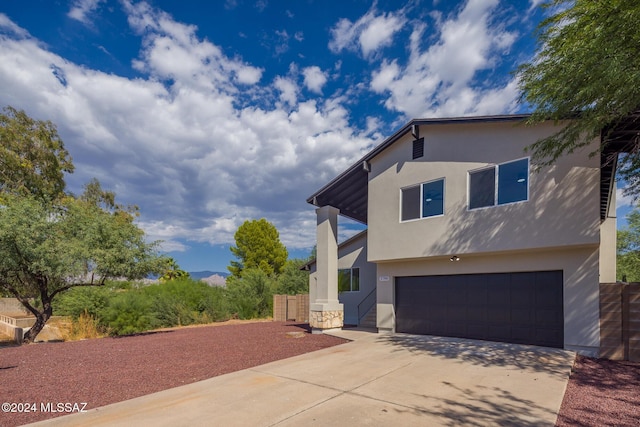 view of side of home featuring an attached garage, stucco siding, and driveway