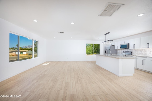 kitchen featuring stainless steel appliances, visible vents, a center island with sink, and light wood-style floors