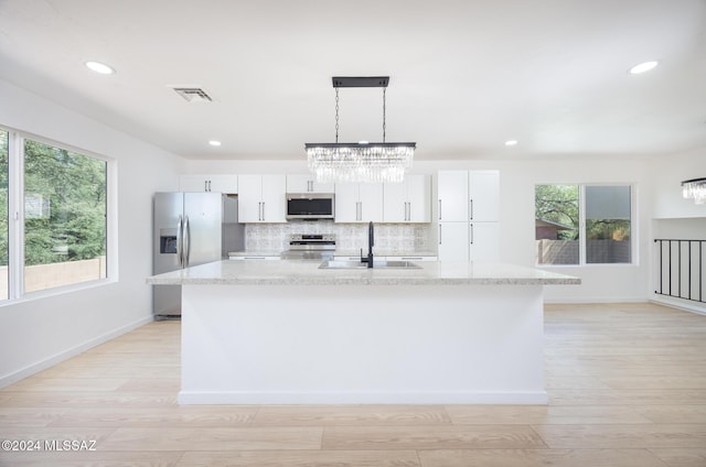 kitchen with an inviting chandelier, visible vents, a center island with sink, plenty of natural light, and appliances with stainless steel finishes