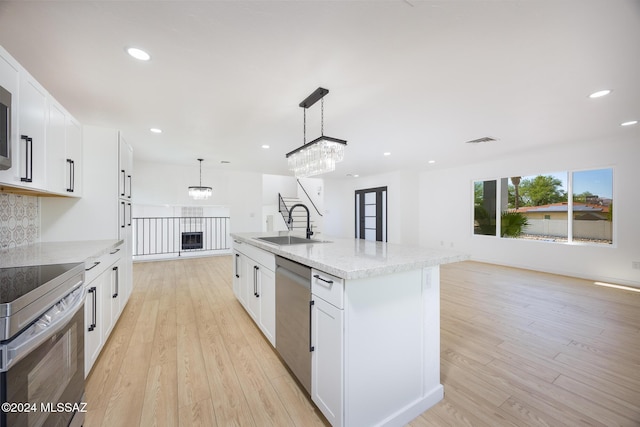 kitchen with visible vents, open floor plan, a sink, light wood finished floors, and stainless steel appliances