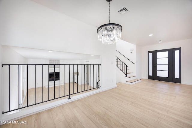 entrance foyer with a notable chandelier, recessed lighting, wood finished floors, visible vents, and stairway