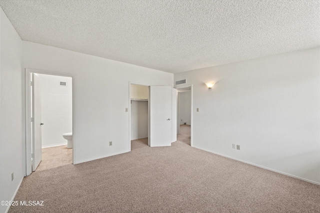 9770 E Hollow Pl, Tucson, AZ 85748 - unfurnished bedroom with ensuite bathroom, visible vents, a textured ceiling, and light colored carpet