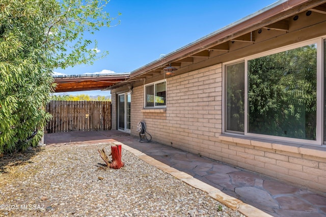 9770 E Hollow Pl, Tucson, AZ 85748 - view of side of home with brick siding, fence, and a patio