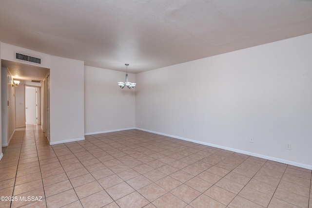 spare room with light tile patterned flooring, visible vents, baseboards, and a notable chandelier