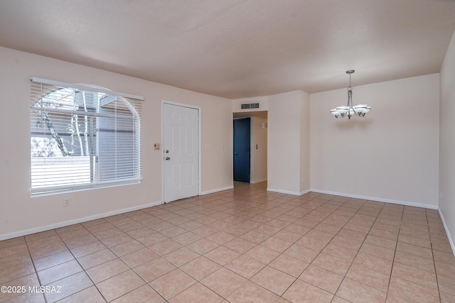 spare room featuring baseboards, visible vents, a chandelier, and light tile patterned floors