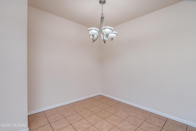 spare room featuring baseboards and a chandelier