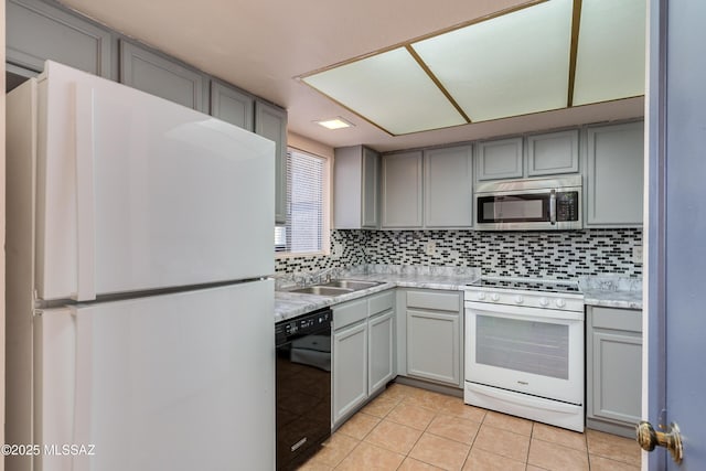 kitchen with light countertops, gray cabinetry, white appliances, and tasteful backsplash