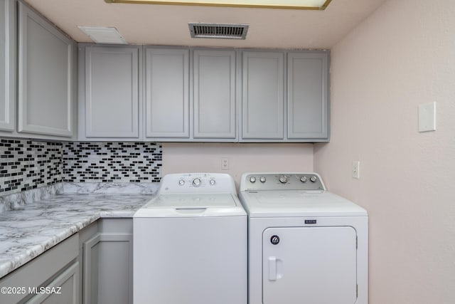 clothes washing area with cabinet space, visible vents, and independent washer and dryer