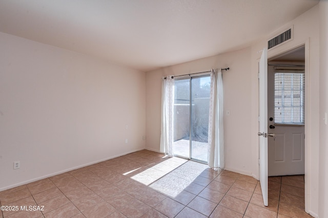 spare room featuring light tile patterned flooring, visible vents, and baseboards