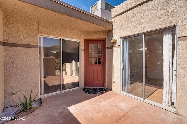 entrance to property with a patio area and stucco siding