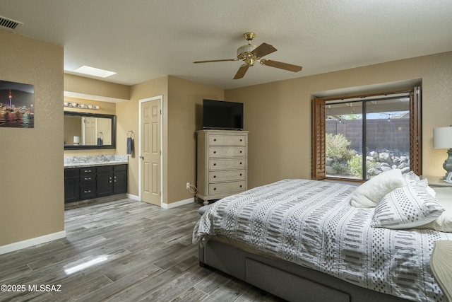 9810 E Amaroso Ln, Tucson, AZ 85748 - bedroom featuring connected bathroom, visible vents, baseboards, wood finished floors, and a skylight
