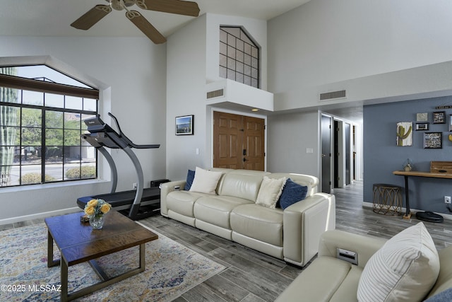 9810 E Amaroso Ln, Tucson, AZ 85748 - living room with visible vents, ceiling fan, baseboards, wood finished floors, and a high ceiling