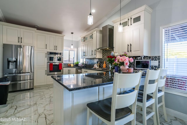 kitchen with appliances with stainless steel finishes, a peninsula, glass insert cabinets, and wall chimney exhaust hood