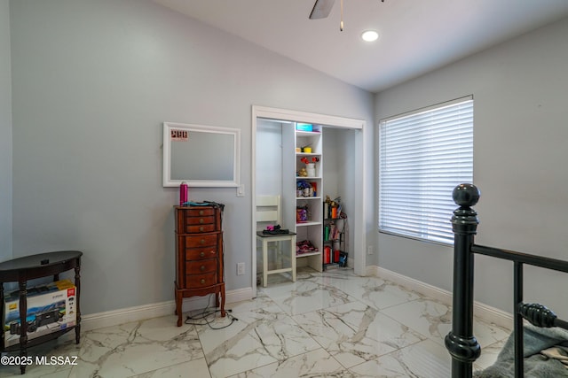 interior space featuring lofted ceiling, marble finish floor, and baseboards