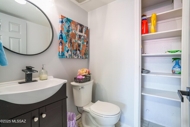 half bathroom with baseboards, toilet, and vanity