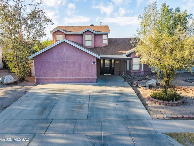 view of front of home with a shingled roof, driveway, an attached garage, and stucco siding