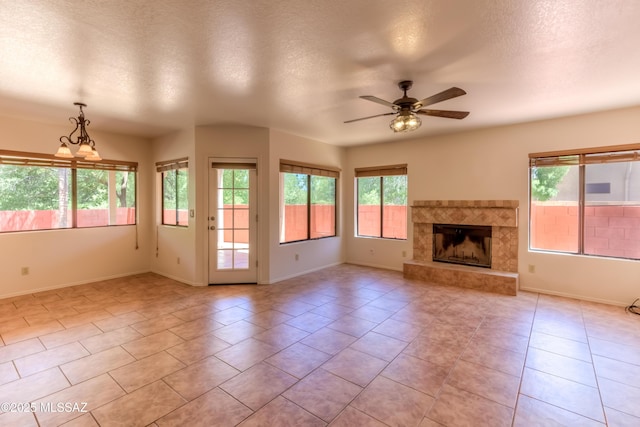 5476 N Indian Trl, Tucson, AZ 85750 - unfurnished living room with a textured ceiling, a wealth of natural light, a ceiling fan, and baseboards