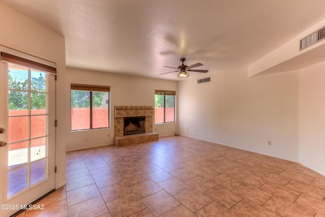 5476 N Indian Trl, Tucson, AZ 85750 - unfurnished living room featuring a tiled fireplace, visible vents, a ceiling fan, and baseboards