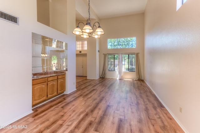 5476 N Indian Trl, Tucson, AZ 85750 - unfurnished dining area with a chandelier, light wood finished floors, baseboards, a high ceiling, and visible vents