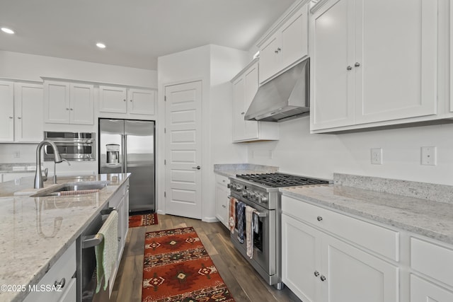 kitchen with white cabinets, premium appliances, range hood, and a sink