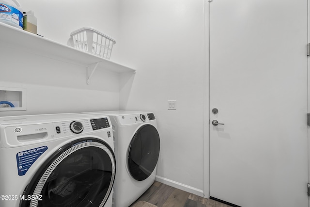 laundry area with wood finished floors, washing machine and clothes dryer, laundry area, and baseboards