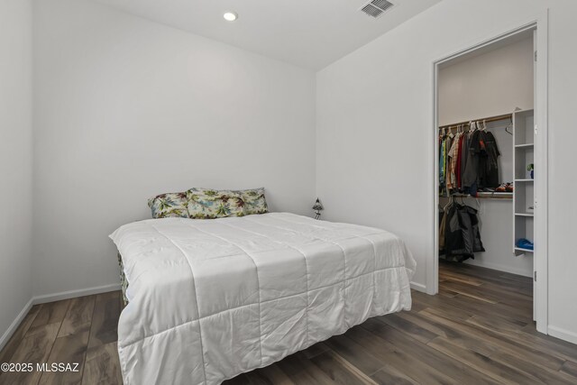 bedroom featuring a walk in closet, visible vents, wood finished floors, and baseboards