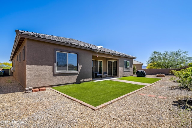 rear view of house featuring stucco siding, a lawn, a patio area, and a fenced backyard