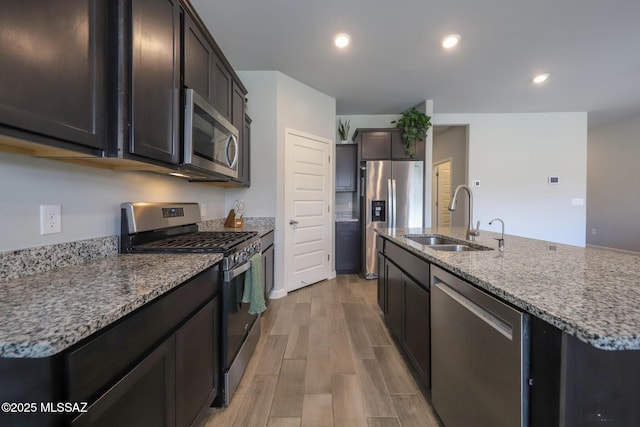 491 W Camino Del Toro, Vail, AZ 85641 - kitchen featuring appliances with stainless steel finishes, a sink, light stone countertops, a kitchen island with sink, and light wood-type flooring