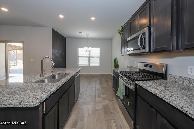 491 W Camino Del Toro, Vail, AZ 85641 - kitchen with stainless steel appliances, a sink, light wood finished floors, light stone counters, and a chandelier