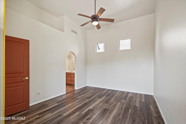spare room with arched walkways, a ceiling fan, dark wood-type flooring, and visible vents