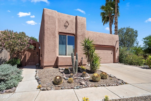 pueblo-style house featuring a garage, stucco siding, and driveway