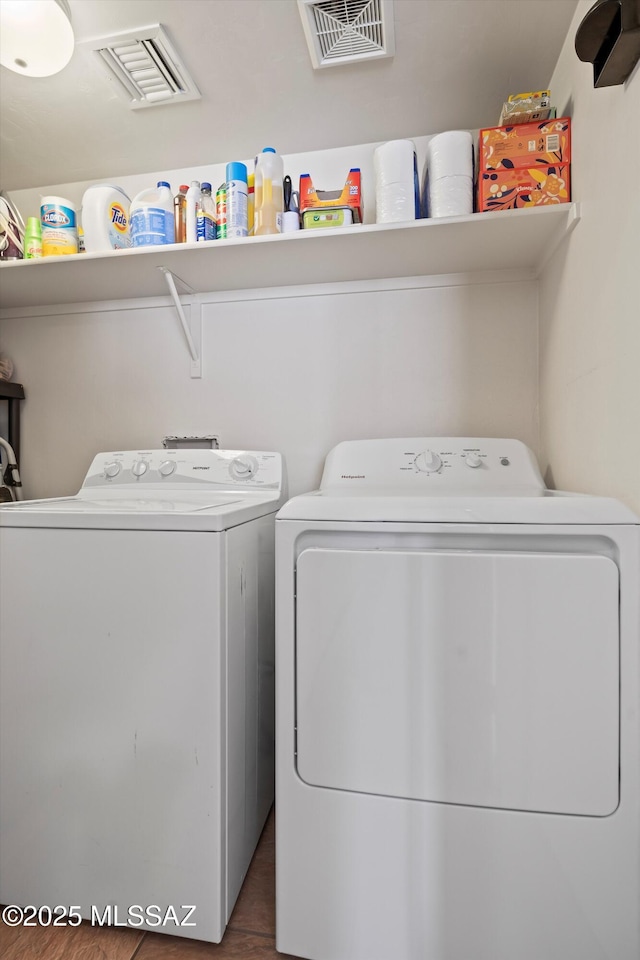 washroom with laundry area, visible vents, and washing machine and dryer