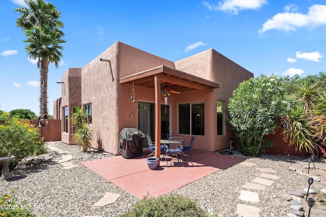 rear view of property with a ceiling fan, a patio area, stucco siding, and fence