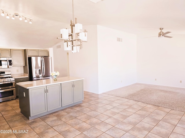 kitchen featuring light countertops, visible vents, a center island, appliances with stainless steel finishes, and ceiling fan with notable chandelier