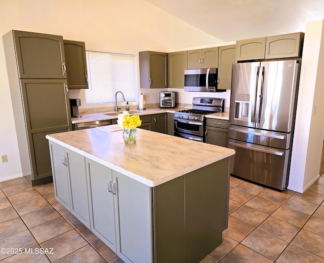 kitchen featuring stainless steel appliances, light countertops, a sink, and green cabinetry