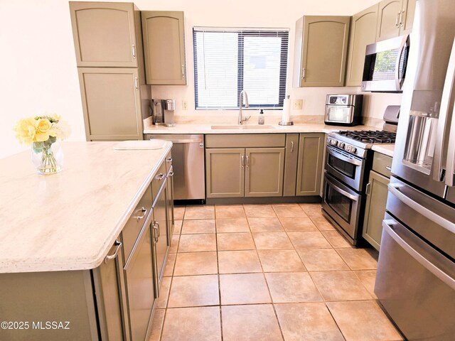 kitchen with stainless steel appliances, a sink, and light tile patterned floors