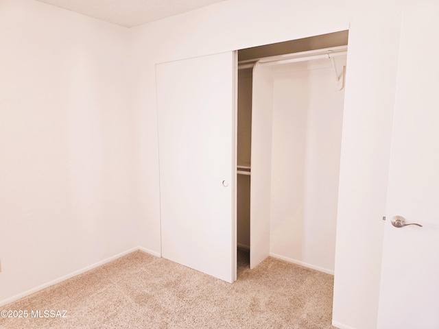 unfurnished bedroom with carpet, a closet, and baseboards
