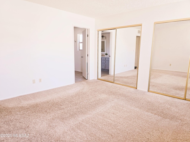 unfurnished bedroom featuring two closets, ensuite bath, carpet flooring, and baseboards