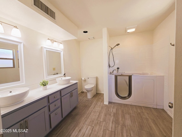 full bath featuring wood finished floors, visible vents, washing machine and clothes dryer, and a sink