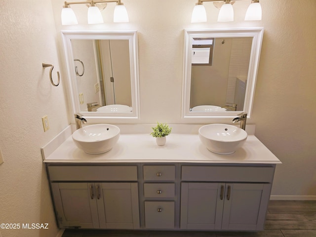 bathroom with wood finished floors, a sink, and double vanity