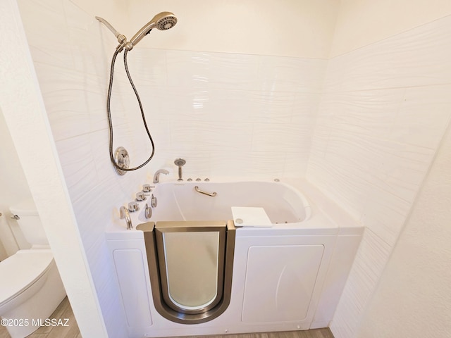 bathroom with a tub to relax in, walk in shower, and toilet