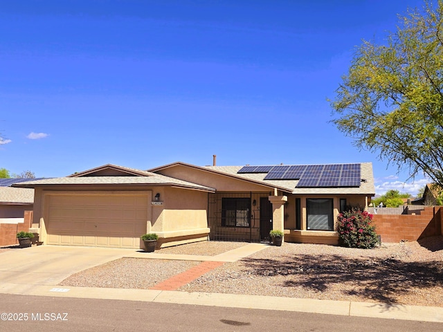 ranch-style home featuring driveway, fence, a garage, stucco siding, and solar panels