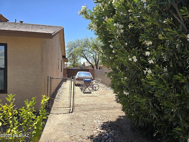 view of side of property featuring fence, a shingled roof, a gate, and stucco siding